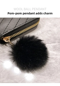 Detail of a soft black wool ball pendant with golden metal clasp on quilted leather purse