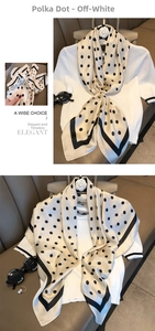 Close-up of beige silk scarf with classic black polka dots and border on a soft surface