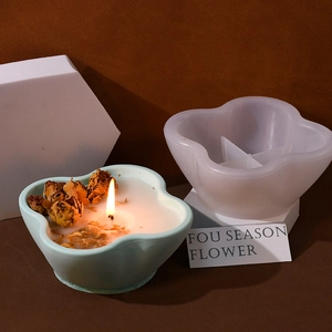 Silicone flower petal candle mold with a finished blue floral candle on a platform