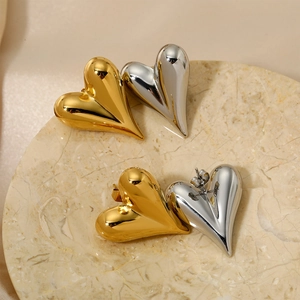 Chic hollow heart stud earrings in gold and silver finish on a marble tray