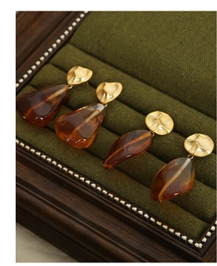 Macro shot of retro amber resin drop earrings on a luxurious dark green velvet tray