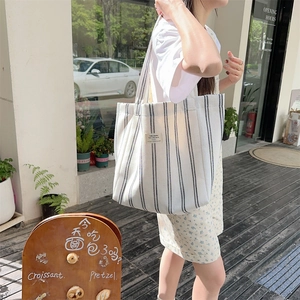Detailed side view of a large striped canvas tote bag in a casual street setting