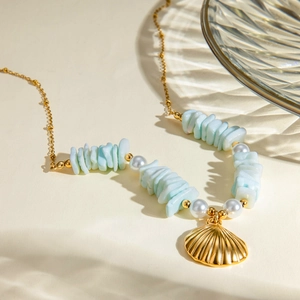 Detail of 18k gold chain necklace with light blue stones, pearls, and shell pendant
