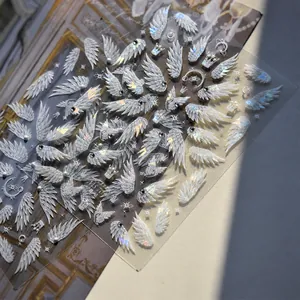 Detailed macro view of 3D iridescent nail stickers with wing, crown, and moon patterns