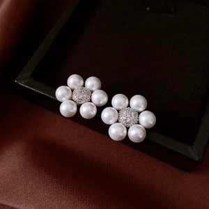 Macro shot of silver pearl flower earrings with rhinestones on black jewelry box