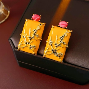 Gros plan sur des boucles d'oreilles vintage en émail jaune avec relief floral doré