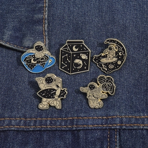 Enamel space pins set on denim jacket featuring astronauts and celestial motifs