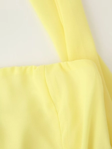Macro shot of yellow chiffon dress shoulder straps and refined stitching detail