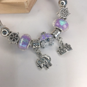 Close-up of beaded charm bracelet with purple glass, elephant, and crown pendants