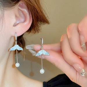 Detailed close-up of silver whale tail earrings with delicate pearls and zircon stones