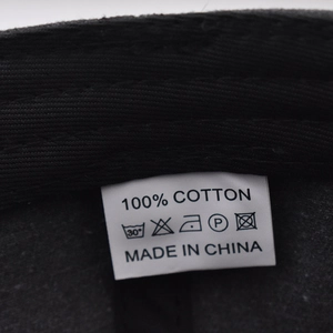 Detail of 100% cotton wash label on black baseball cap with care instructions