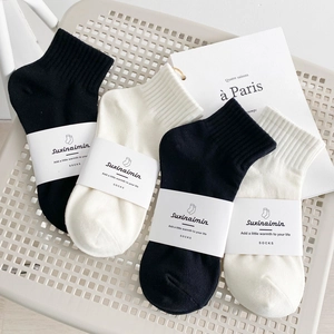 Set di quattro paia di calze in maglia bianche e nere su una sedia a rete minimalista