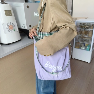 Canvas tote bag detail showing lavender body with Bonjour magic print and plaid strap