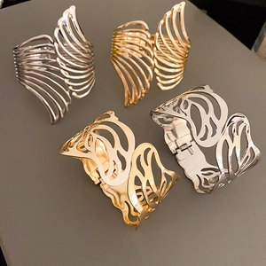 Detail of gold and silver hollow leaf pattern wide metal cuffs with open adjustable design