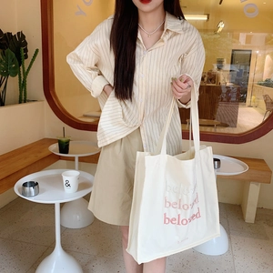 Women in striped shirt with white canvas tote bag featuring red beloved embroidery