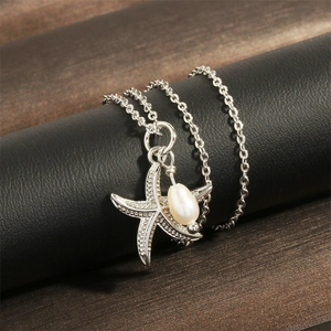 Macro detail of silver starfish pendant with shimmering pavé diamonds and drop pearl