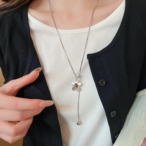 Detail of silver Y-shaped flower necklace with brown gemstone and pearl accents
