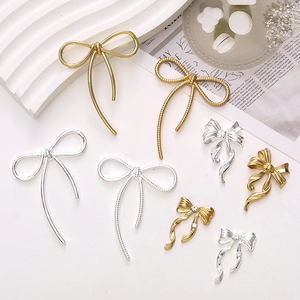 Detailed view of silver and gold zinc alloy bow charms with rhinestones on a white surface