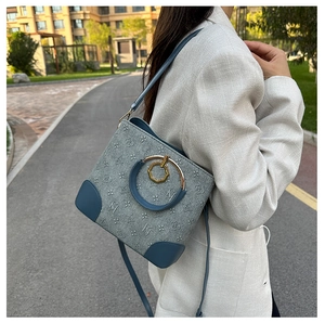 Detail of grey-blue bucket bag featuring all-over pattern and gold hardware on model