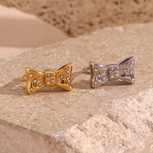 Macro detail of gold and silver bow-knot rings with inlaid crystals on natural stone