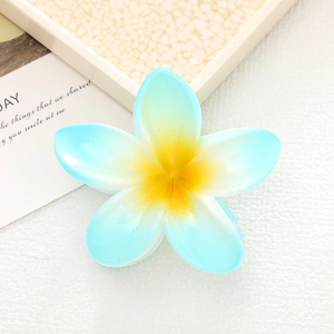 Detail of blue and yellow gradient plumeria hair claw clip on a minimalist background
