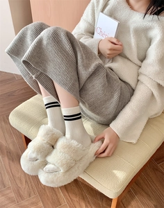 Close-up of cozy beige plush slippers with black and white striped wool socks for winter