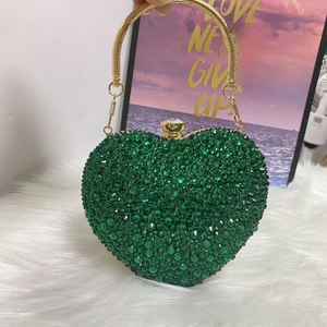 Close-up of heart-shaped rhinestone evening bag with green crystals and gold handle