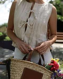 Detail of pleated beige linen vest featuring delicate double tie closures and a soft texture