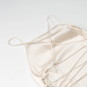 Dettaglio dell'elegante abito in raso crema con lacci incrociati sulla schiena e trama in seta