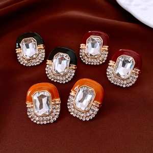 Detailed macro view of vintage gold stud earrings with colorful enamel and inset crystals