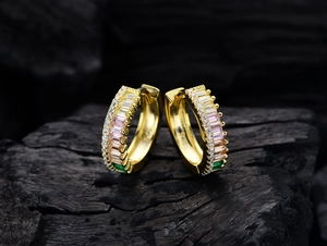 Macro shot of 925 silver gold-plated hoop earrings with rainbow baguette zircons