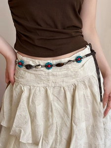 Détail de chaîne de taille bohème perlée avec fleurs bleues et accents coquillage