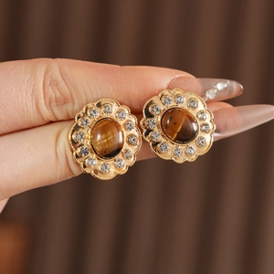Dettaglio di orecchini vintage in oro con pietra occhio di tigre e strass di cristallo