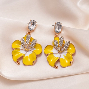 Dettaglio di orecchini vintage a fiore con petali in smalto giallo e cristalli lucidi