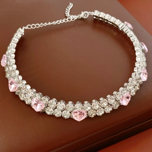 Vue macro d'un collier argenté avec cœur rose et cristaux clairs sur une boîte à bijoux