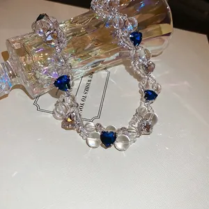 Elegant beaded heart necklace with blue crystals wrapped around a glass perfume bottle
