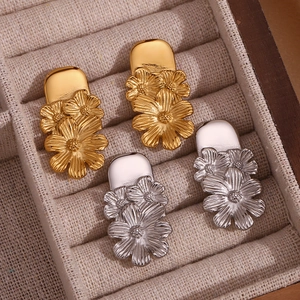 Macro shot of gold and silver daisy earrings with brushed metal texture in a jewelry box