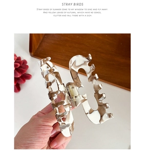Detail of large acetate hair claw clip featuring brown marble patterns and gold metal spring