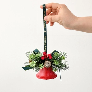 Red Christmas bell ornament with pine needles and cones on a Merry Christmas ribbon