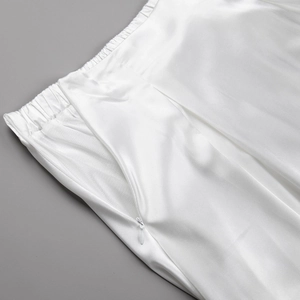 Detail view of white satin skirt featuring elastic waistband and invisible side zipper