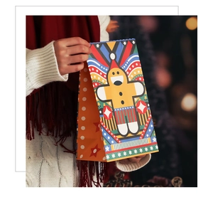 Detail of hand-held Christmas kraft paper bag featuring a cute gingerbread man illustration
