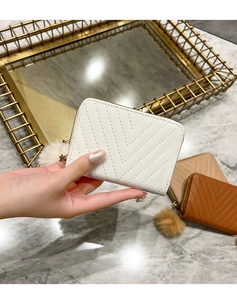 Detail of V-quilted faux leather wallet with fluffy pompom and smooth gold zipper