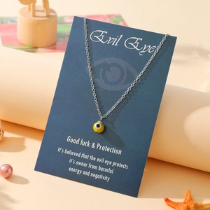 Detail of evil eye pendant necklace with yellow charm on a blue message card display