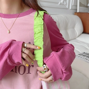 Close-up of pink long-sleeve tee paired with green pleated shoulder tote bag