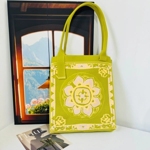 Close-up of green knit tote bag with floral jacquard pattern and woven texture