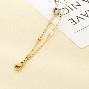 Detailed view of gold double-layer anklet with a heart-shaped stone and white pearl beads