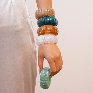Close-up of layered acrylic geometric bangles in amber and emerald tones for women