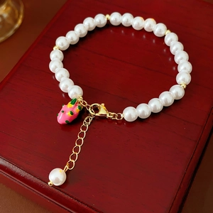 Detail of gold-plated pearl bracelet with strawberry pendant on red wood box