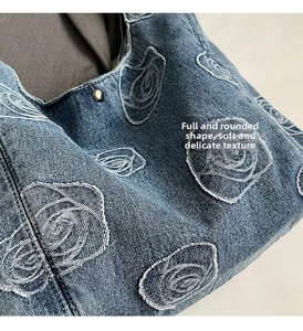 Detail of rose embroidery and silver rivet on blue denim tote bag for women
