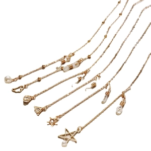 Golden metal eyewear chain with pearls and star pendants on a clean white background